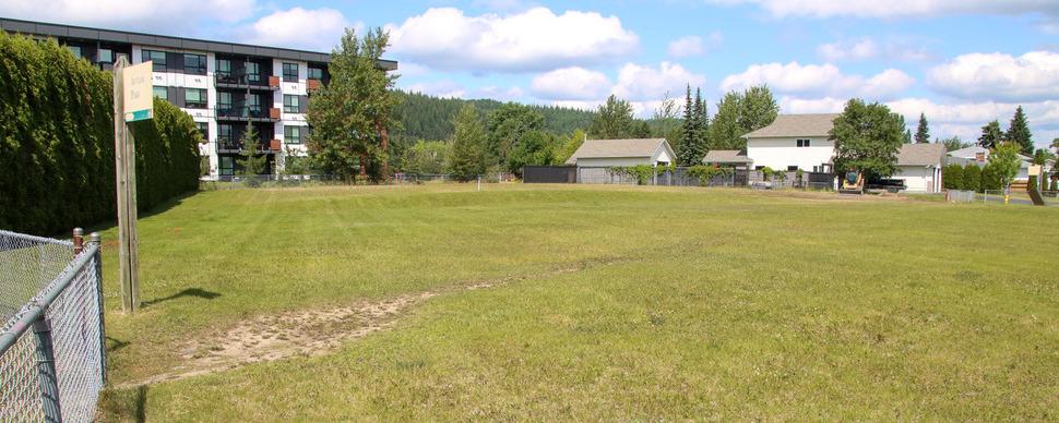 A grassy field next to apartment buildings and single family homes